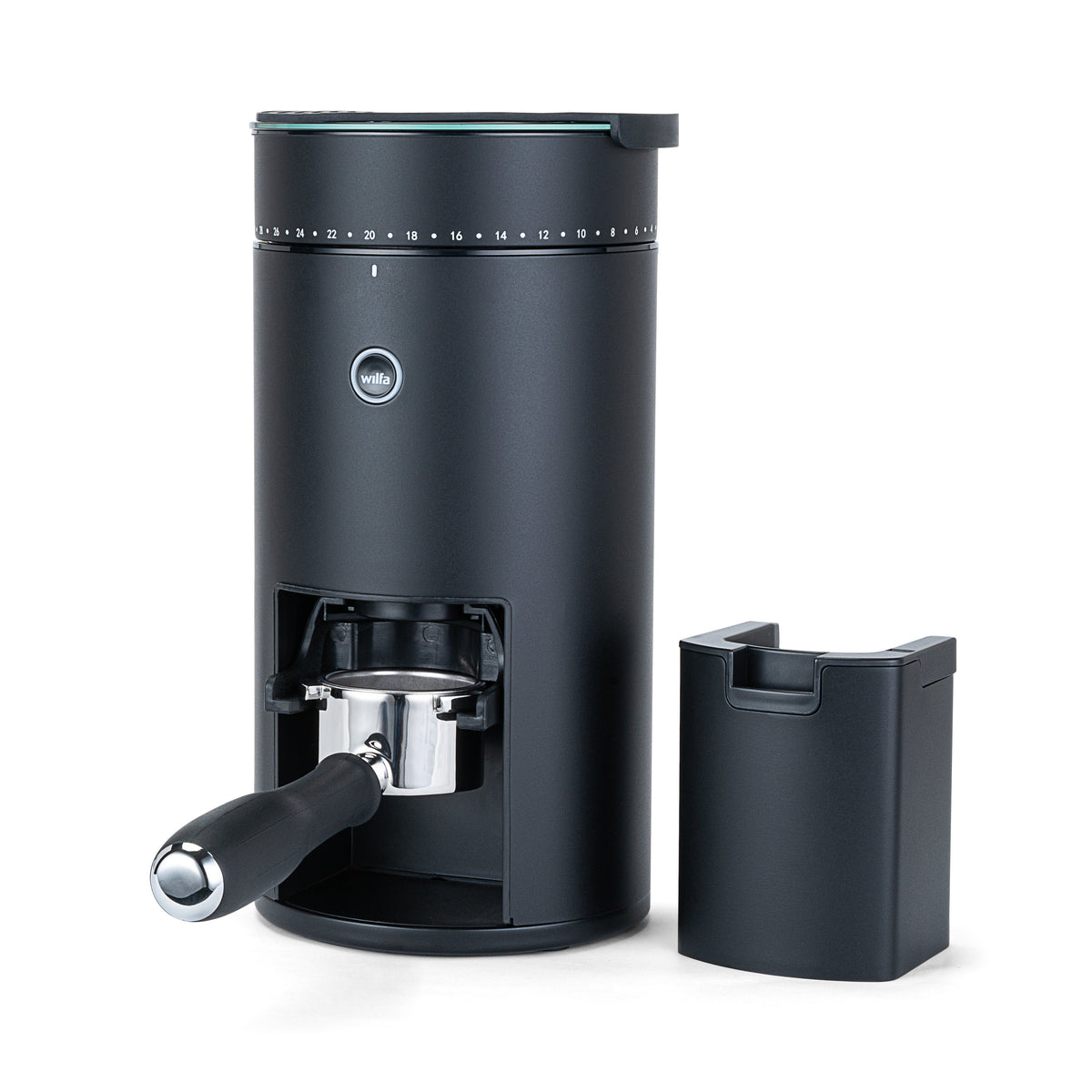 Wilfa Uniform Evo black coffee grinder with a portafilter placed in the holder, shown next to the grounds container.