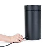 A hand plugging the power cord into the back of the Wilfa Uniform Evo black coffee grinder.