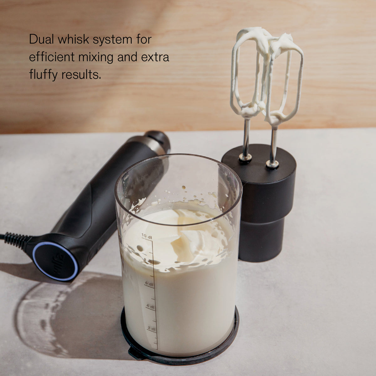 Wilfa Prostick immersion blender with the dual whisk attachment next to a measuring jug of whipped cream, with the text 'Dual whisk system for efficient mixing and extra fluffy results.'